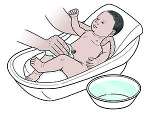Main tenant un linge pour laver un bébé dans une bassine d’eau.
